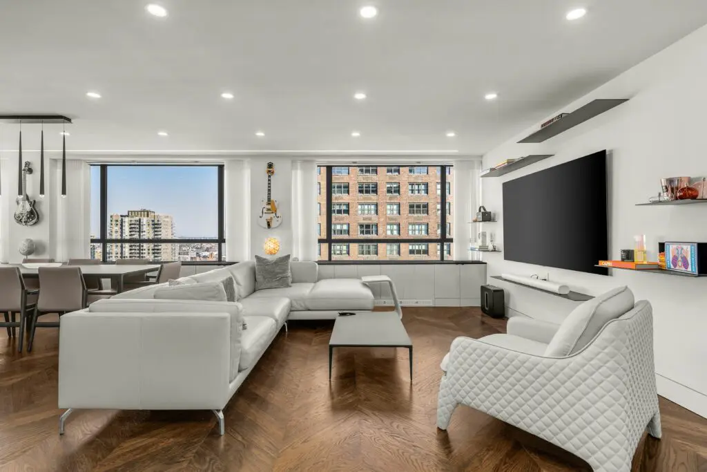 Luxury home remodeling in nyc by top general contractor, image features white luxury couches, wooden floors and New York view in a window