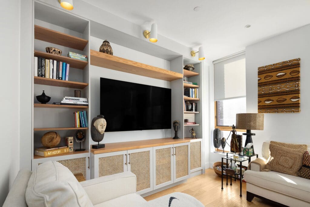 Modern NYC apartment living room renovation with custom built-in entertainment center, natural wood shelves, and decorative accents