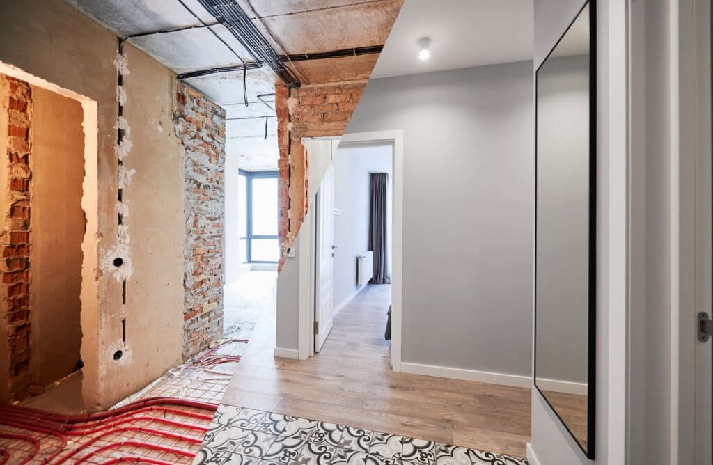 A split-view image showing a hallway before and after gut renovation; the left side is unfinished with exposed brick and wires, while the right side is modern, clean, and fully finished with painted walls and wooden flooring.