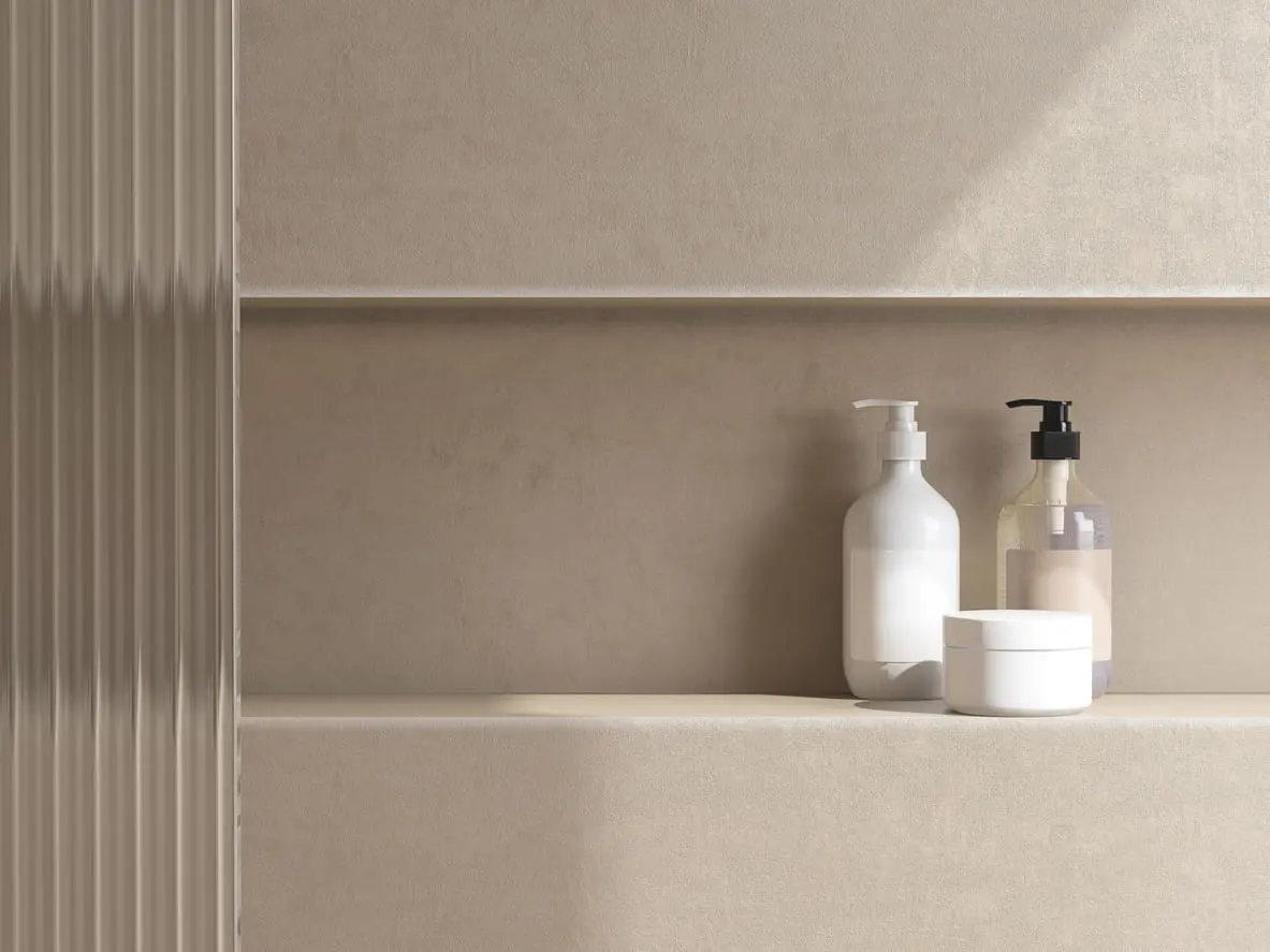 Minimalist bathroom shelf with three items:  Single Niche, a white pump bottle, a clear bottle with a black pump, and a white round container, all set against a beige textured wall with soft natural lighting.