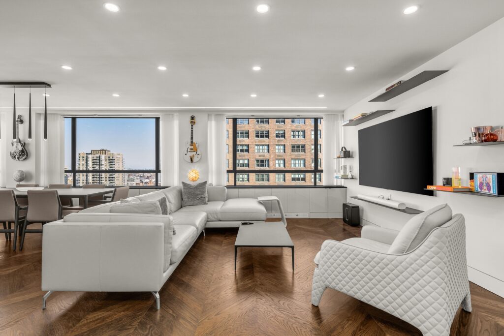 Luxury home remodeling in nyc by top general contractor, image features white luxury couches, wooden floors and New York view in a window