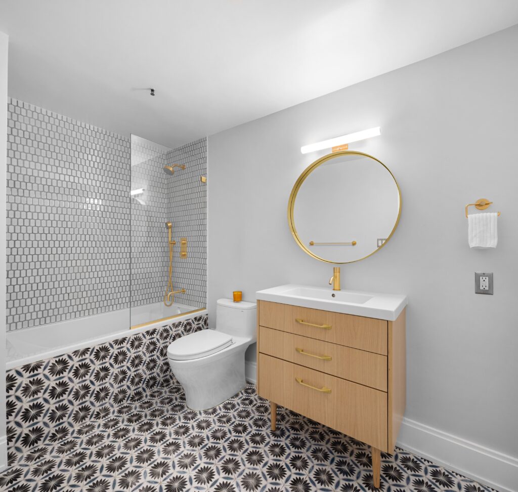 Luxury bathroom renovation in NYC featuring a freestanding soaking tub, textured accent wall with LED backlighting, and modern matte black fixtures