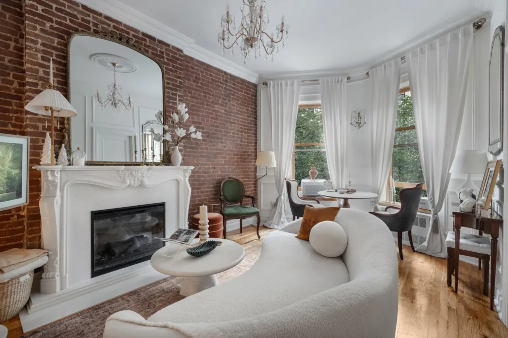 Upper West Side living room renovation with exposed brick, fireplace, and white sofa